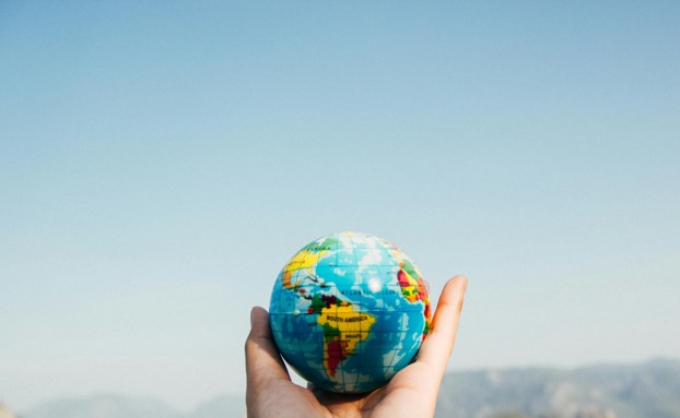 twee handen houden een wereldbol in de lucht